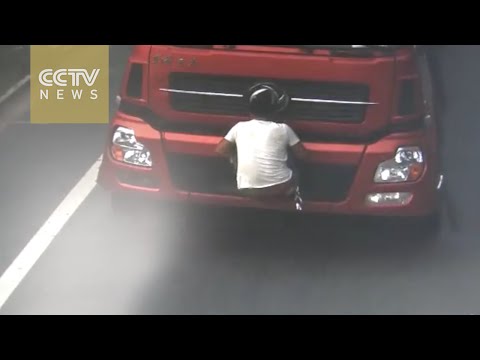 بالفيديو شاهد تبّاع يغطي لوحات شاحنة بجسده هربا من شرطة المرور