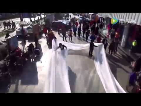 سيدة تبهر سكان الصين بعد سيرها في الشارع بفستان زفاف «طوله 100 متر»